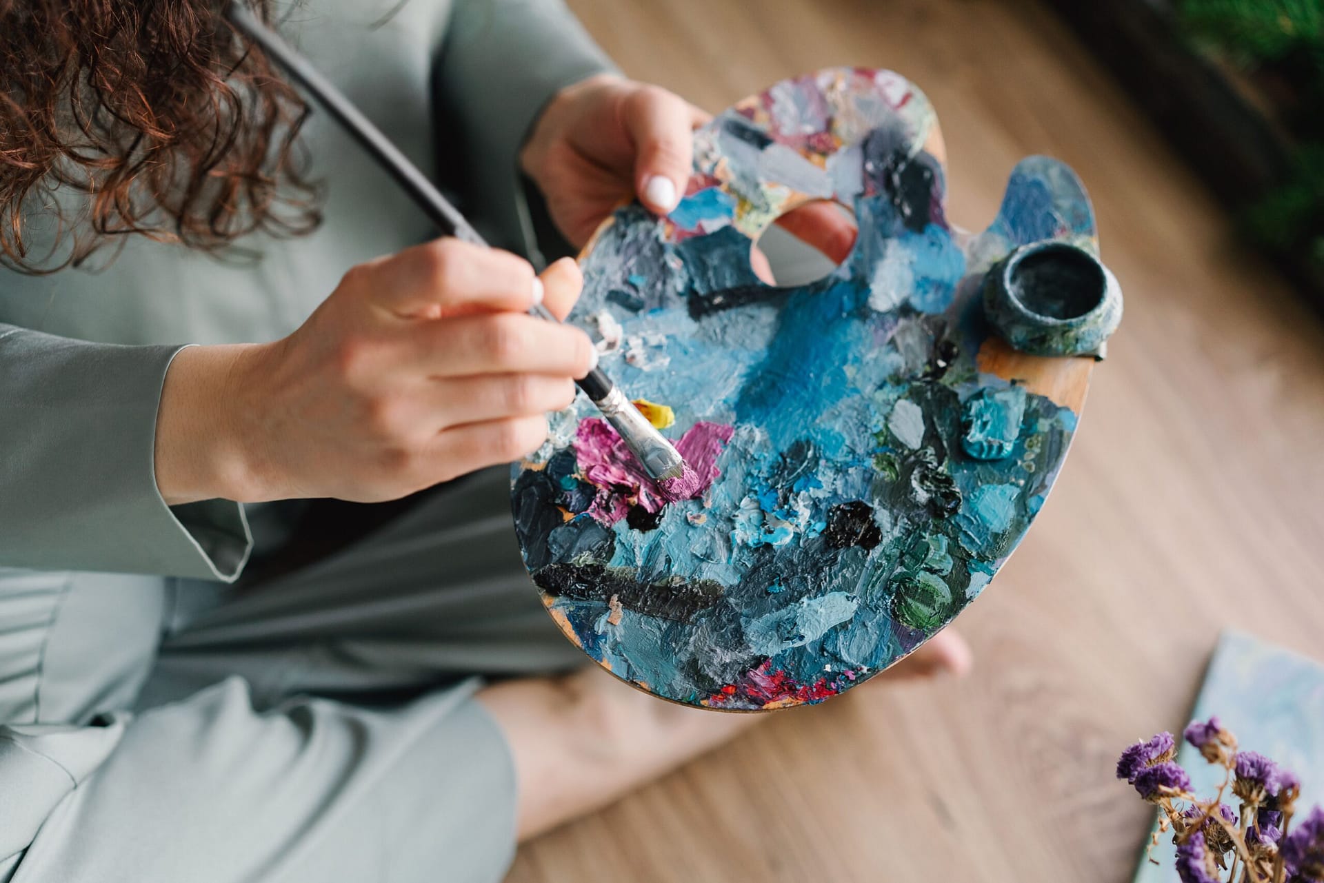 Close-up of hands painting on a colorful palette, showcasing creativity and artistry.